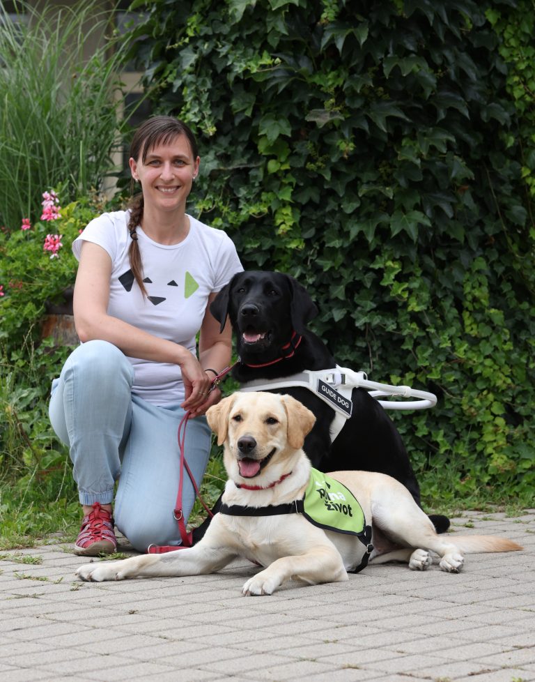 Ivana kneeling next to a yellow labrador