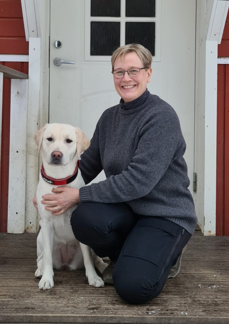 Minna kneeling down next to a yellow labrador